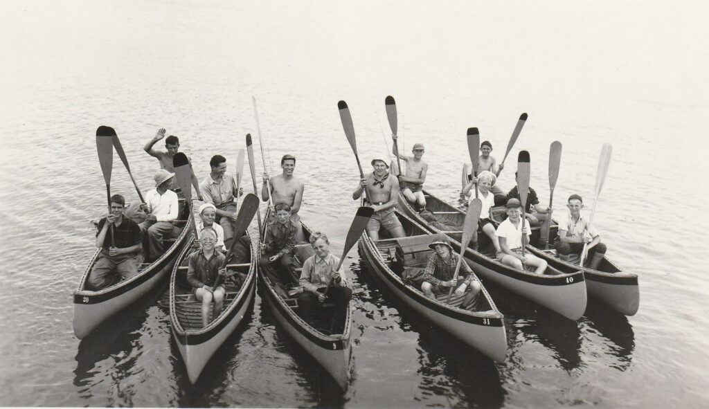 Group paddling canoes on a lake.