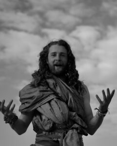 Man with long hair gestures outdoors