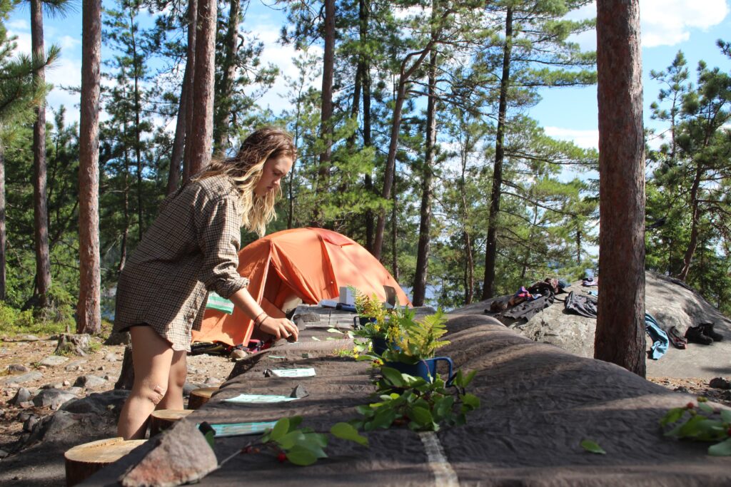 Woman arranging plants at forest campsite