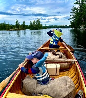 Children canoeing on lake under cloudy sky