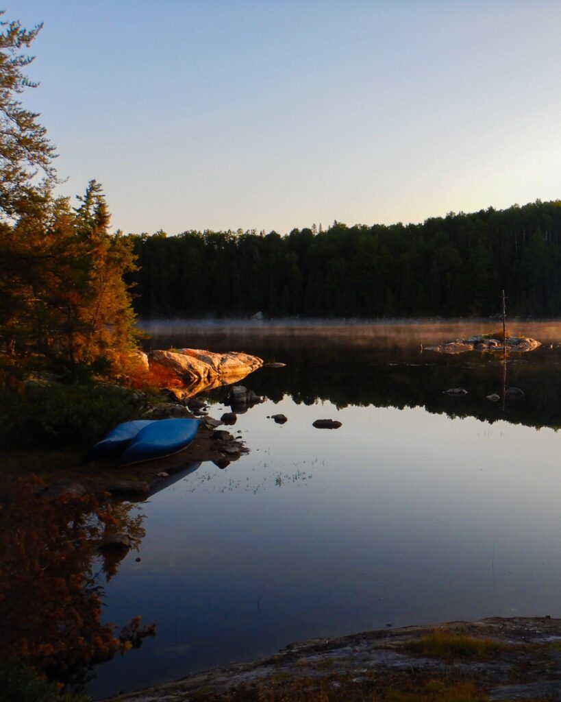 Serene lake with canoes and trees at sunset