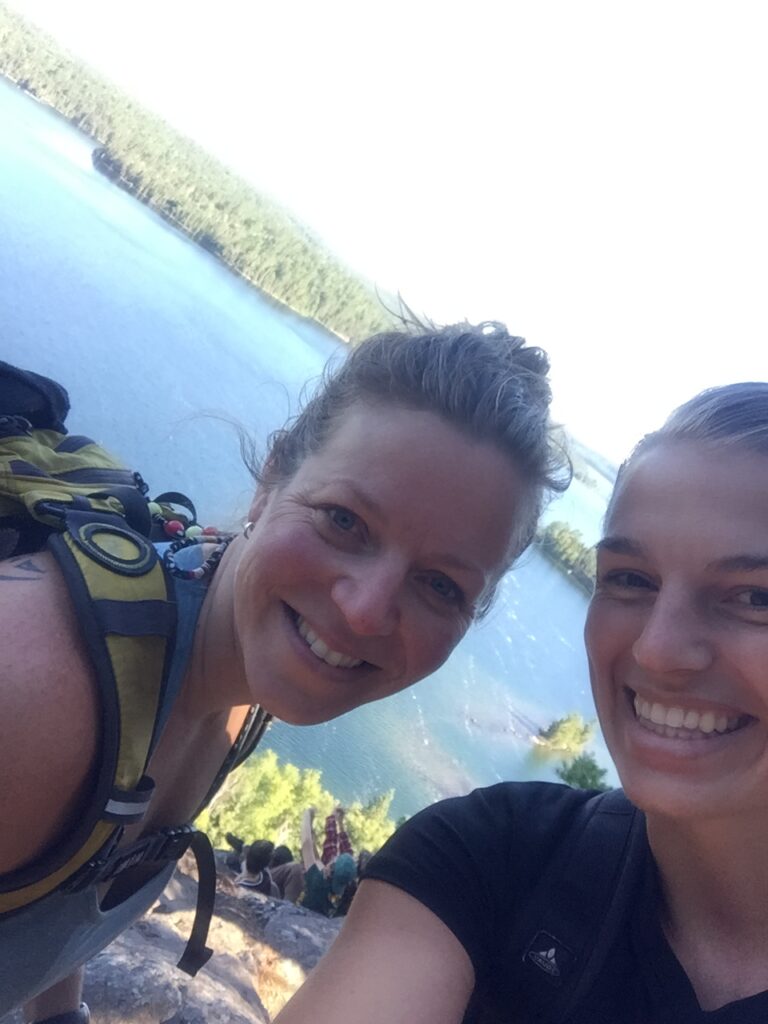 Two hikers smiling by scenic lake view.